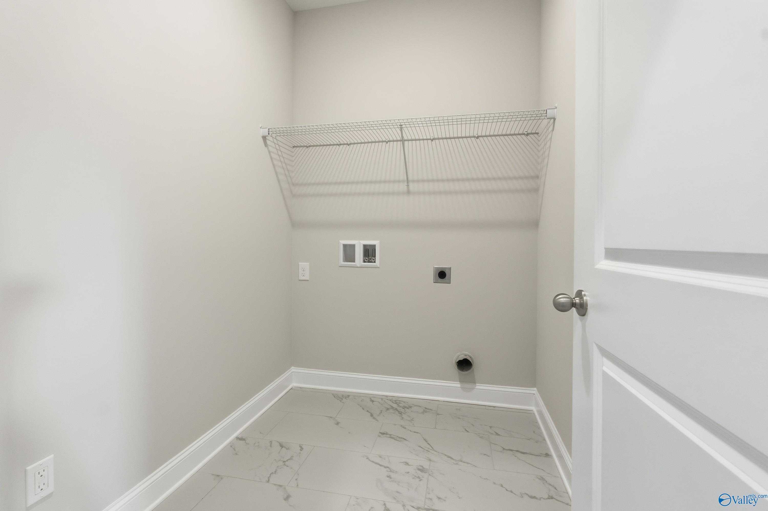 Spacious laundry room with wire shelving, washer/dryer hookups and marble-look flooring in Davidson Homes Montgomery B, Toney, AL