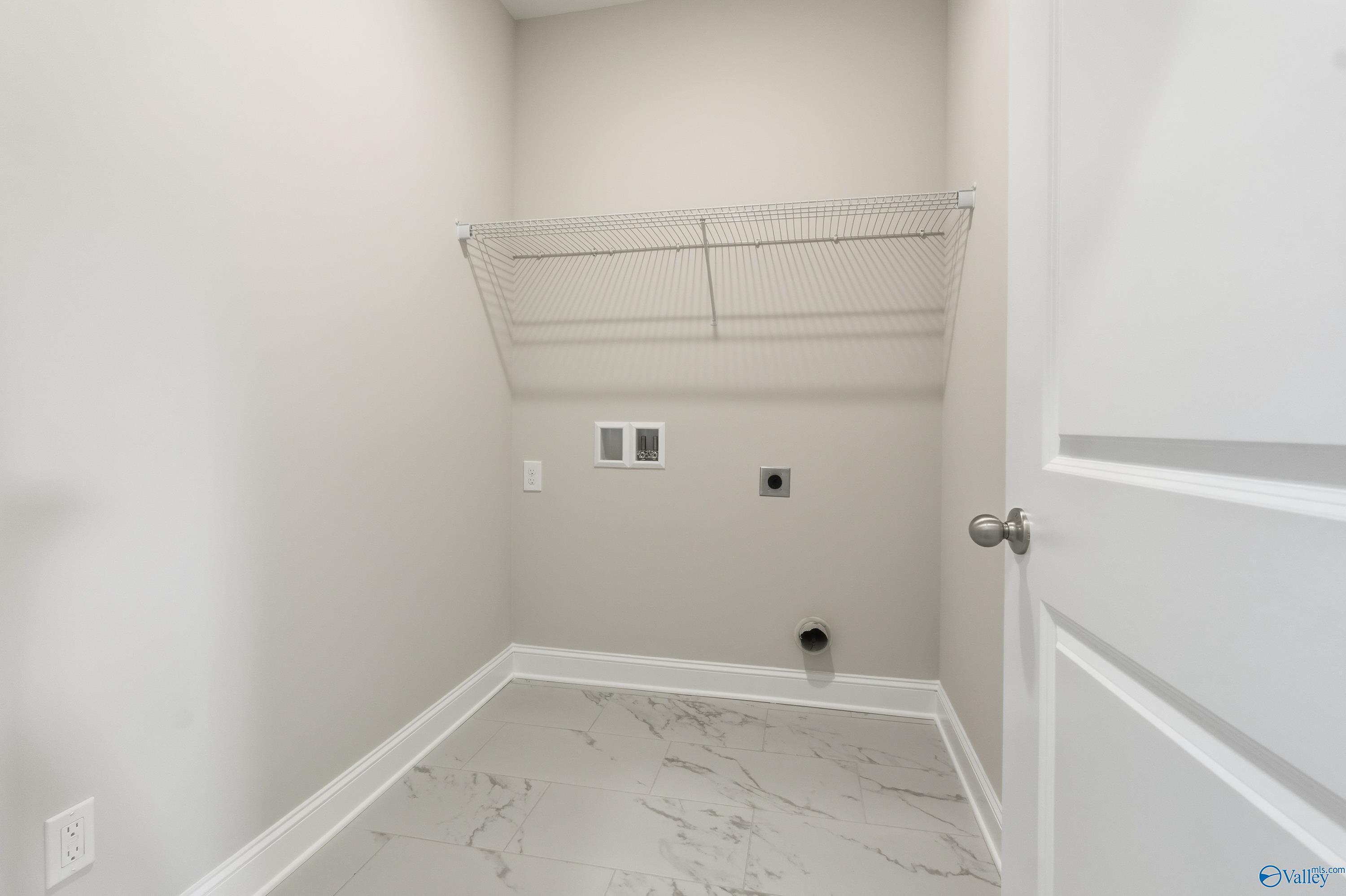 Spacious laundry room featuring wire shelving, washer/dryer hookups, and marble-look tile floor in Davidson Homes Montgomery B, Toney, Alabama