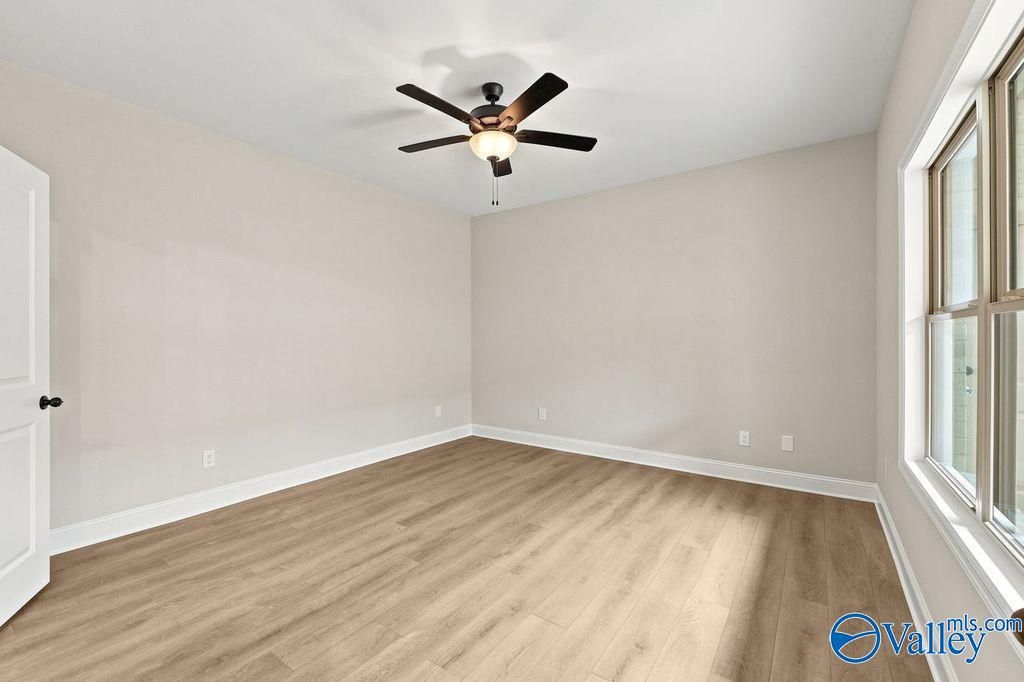 Bright, spacious bedroom with wood-style flooring and ceiling fan in The Camilla C floor plan at The Retreat at Cain Park.