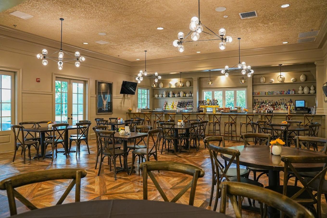 Elegant clubroom bar at Addison West in Holly Springs NC with wooden tables, chairs, pendant lights and stocked shelves