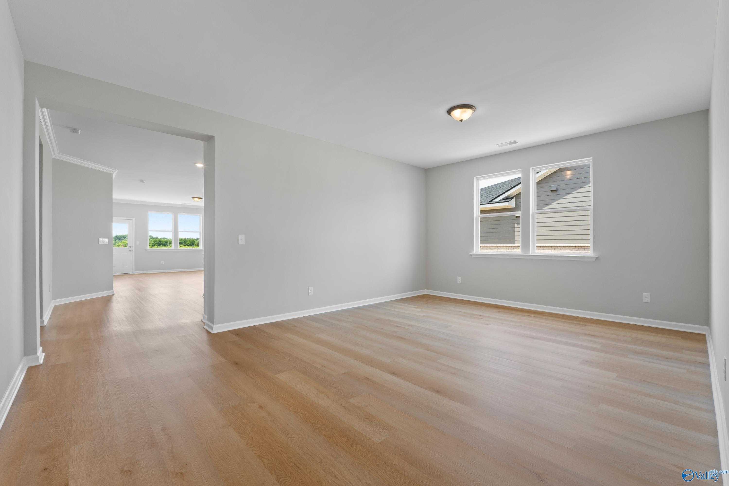 Spacious empty bedroom with gray walls, oak hardwood floors, large windows, and open layout in Davidson Homes The Orion, Athens AL