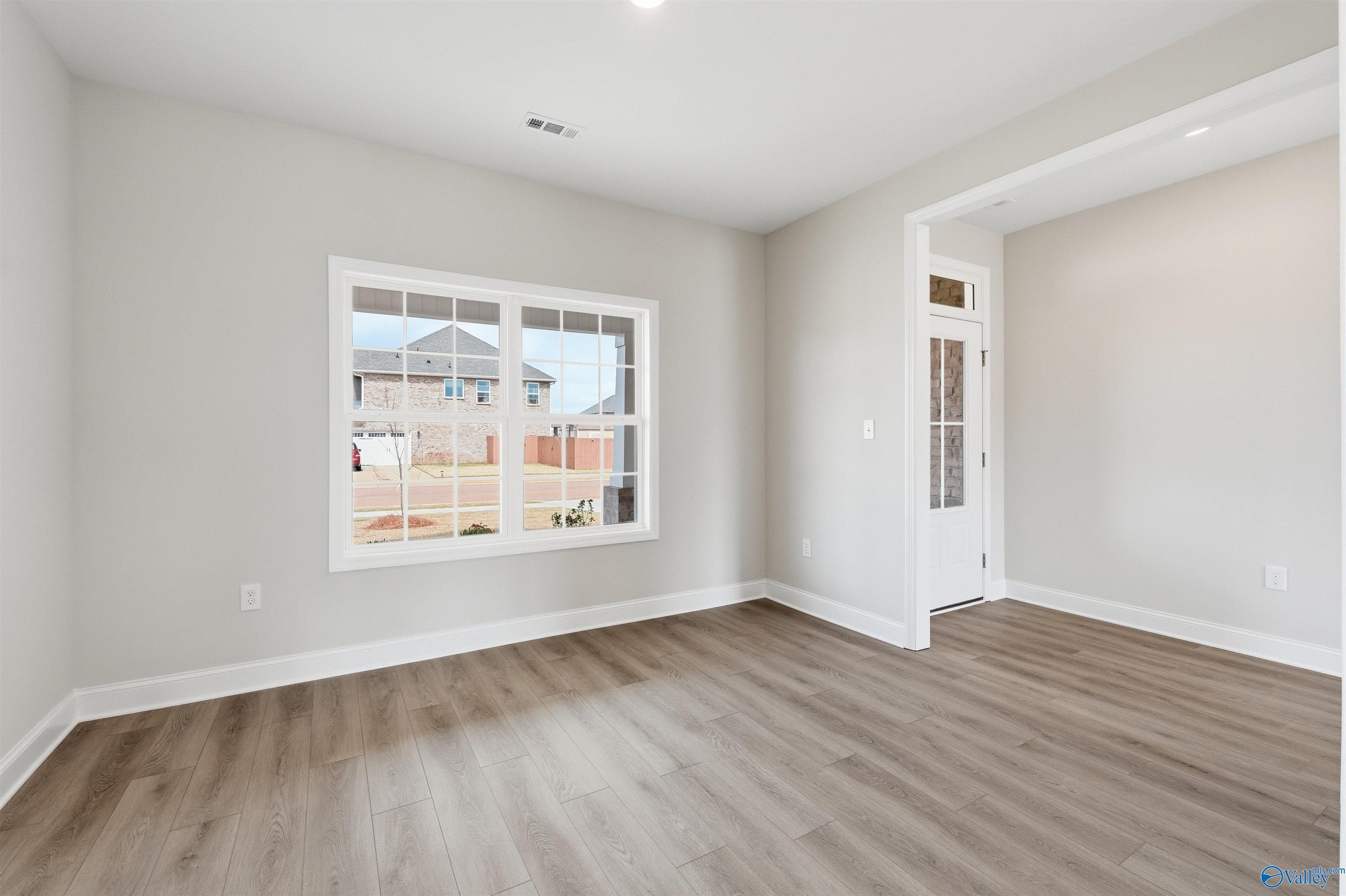 Bright, neutral-toned room with wood-look flooring and large windows in The Shelby D floor plan at Evergreen Mill, Madison.