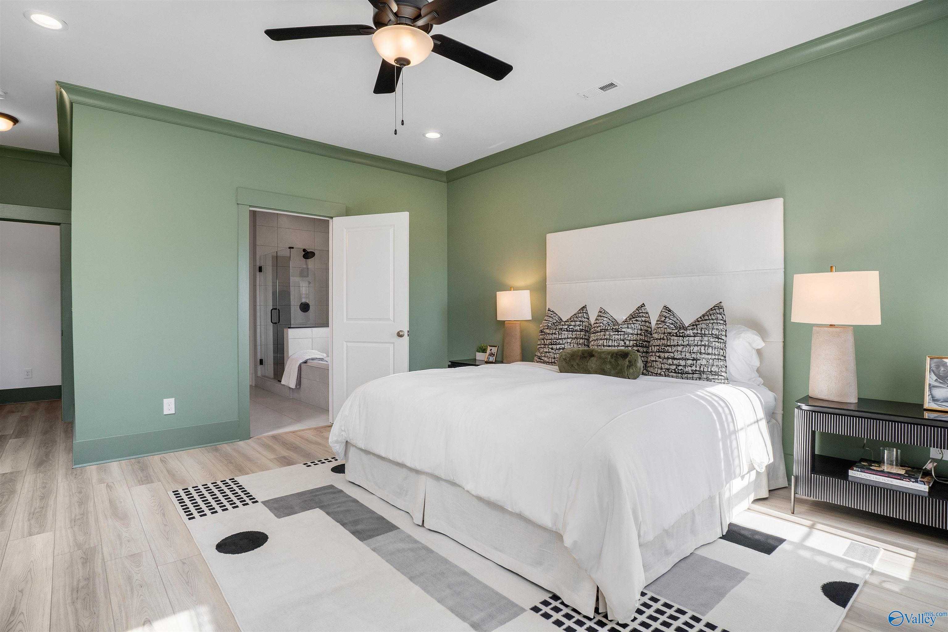 Elegant master bedroom with sage green walls, king bed, ceiling fan, en-suite bath in Davidson Homes The Rockford B, Madison, AL