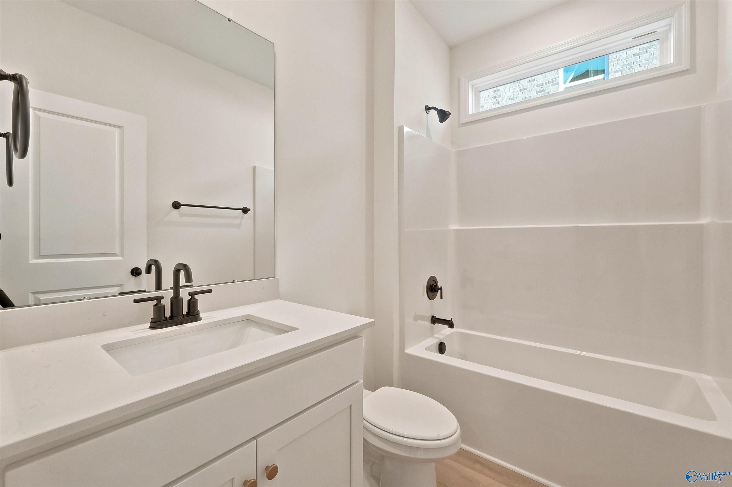 Modern bathroom with white vanity and tub-shower combo in The Chelsea C floor plan at Creek Grove, New Market, Alabama.