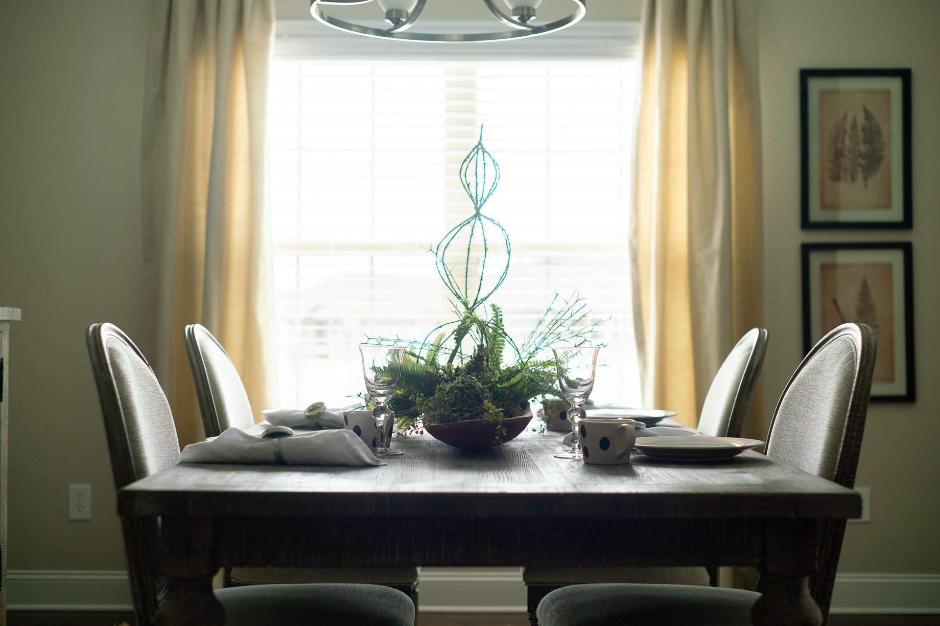 Spacious dining room at The Dairy at Oak Grove in South Huntsville AL with wooden table, upholstered chairs, and green plant centerpiece