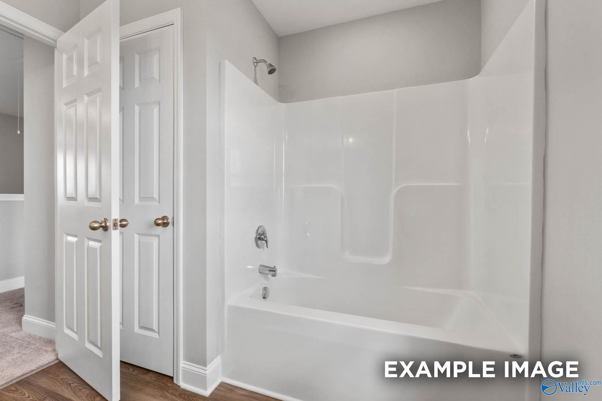 Modern bathroom featuring white tub-shower combo with glass doors in Davidson Homes The Shelby B, Athens, Alabama