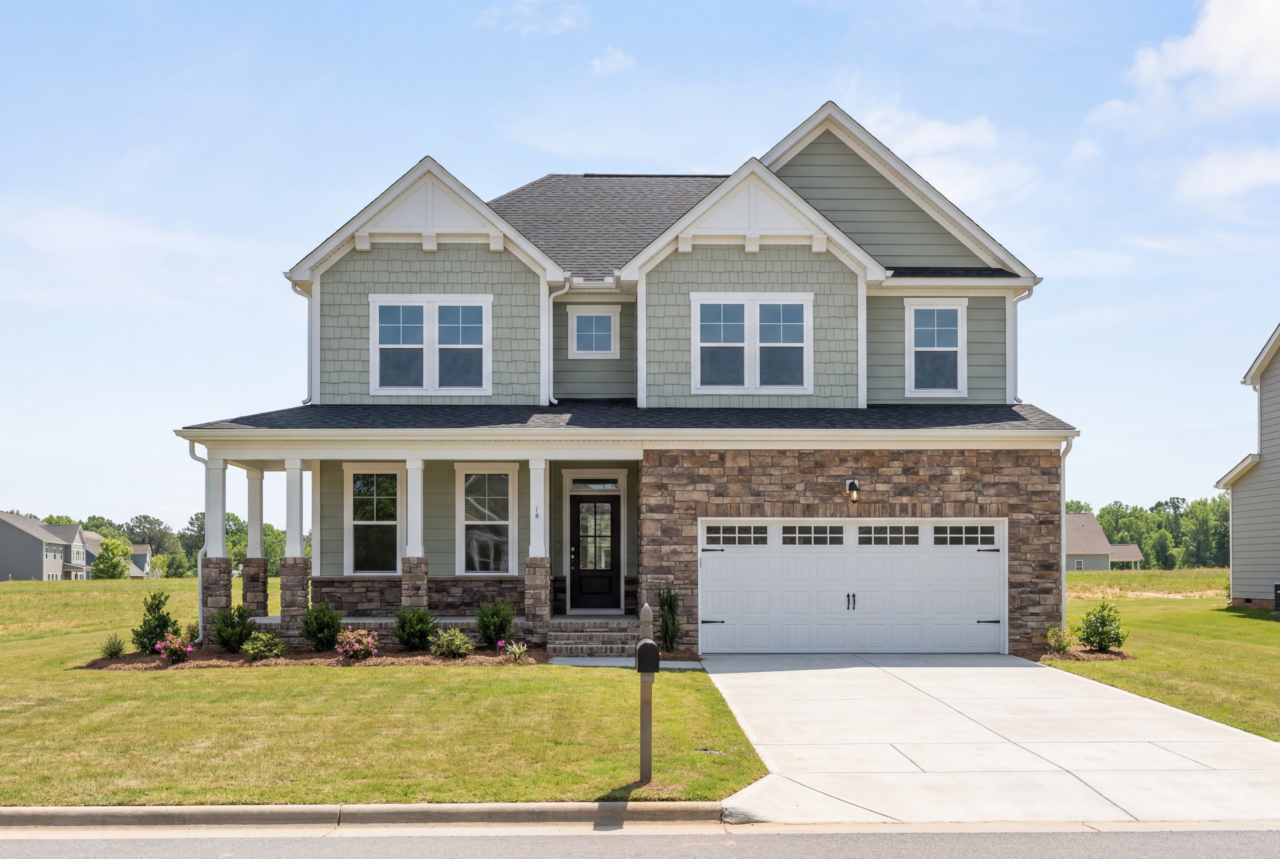 Two-story The Willow G home elevation in gray siding, brick accents, covered porch, and 2-car garage by Davidson Homes in Wake Forest NC
