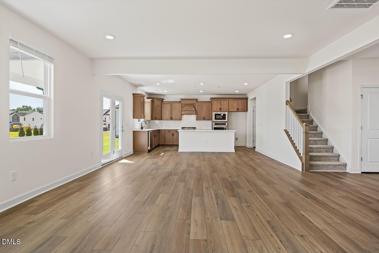 Open-concept living area with hardwood floors, kitchen island, and staircase in Davidson Homes The Hickory II B, Lillington, NC