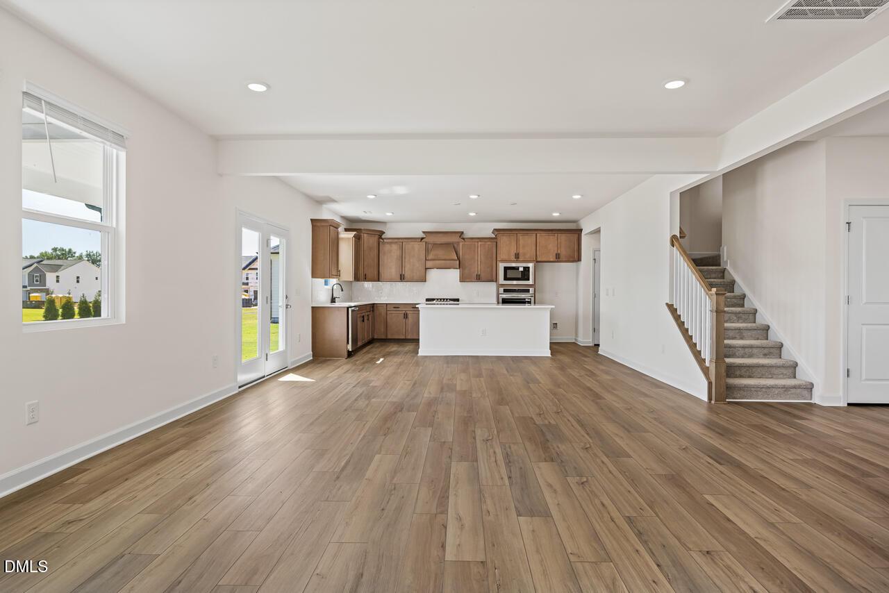 Open-concept living area with hardwood floors, kitchen island, and staircase in Davidson Homes The Hickory II B, Lillington, NC