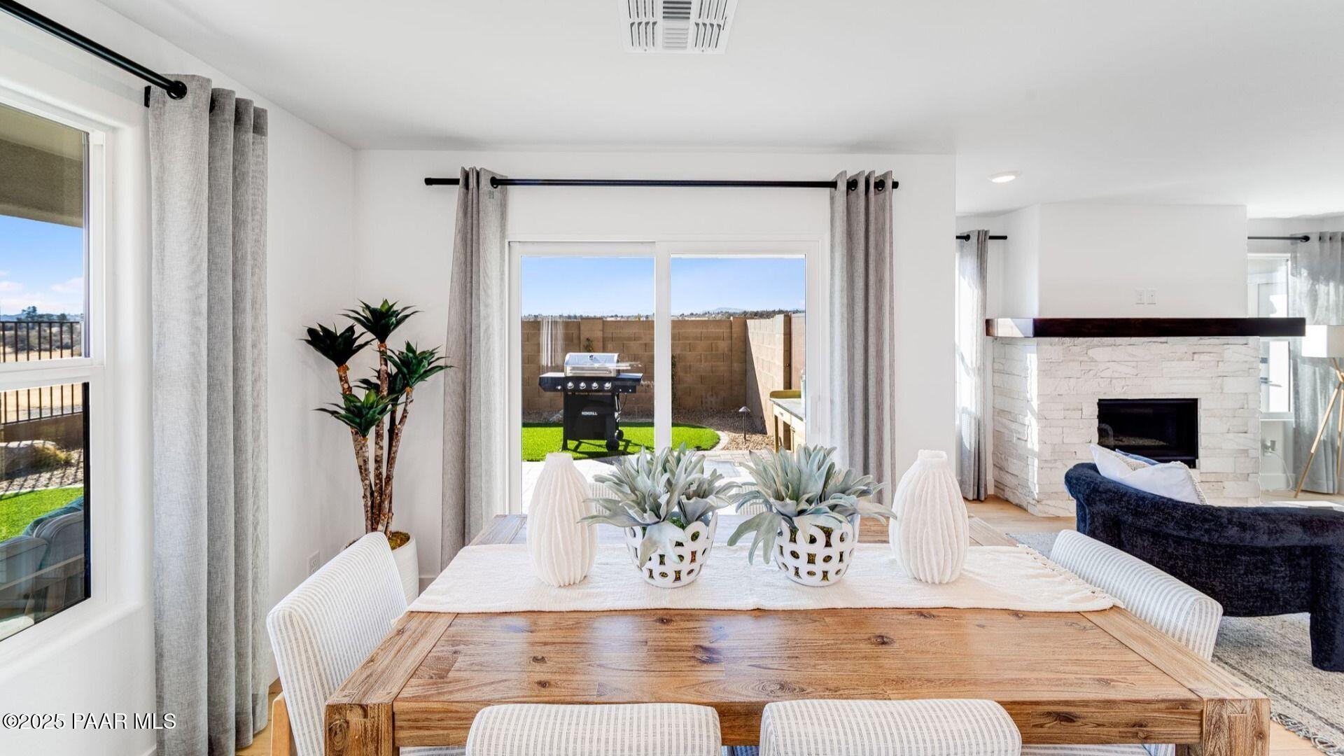 Bright dining room with rustic wood table, potted succulents, and sliding doors to covered patio in Davidson Homes Wilmington B, Prescott AZ