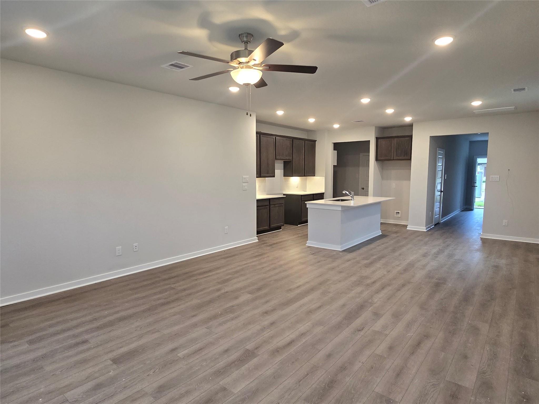 Modern open-concept kitchen with dark shaker cabinets, white island, and hardwood floors in The Brazos E home, Cleveland, Texas