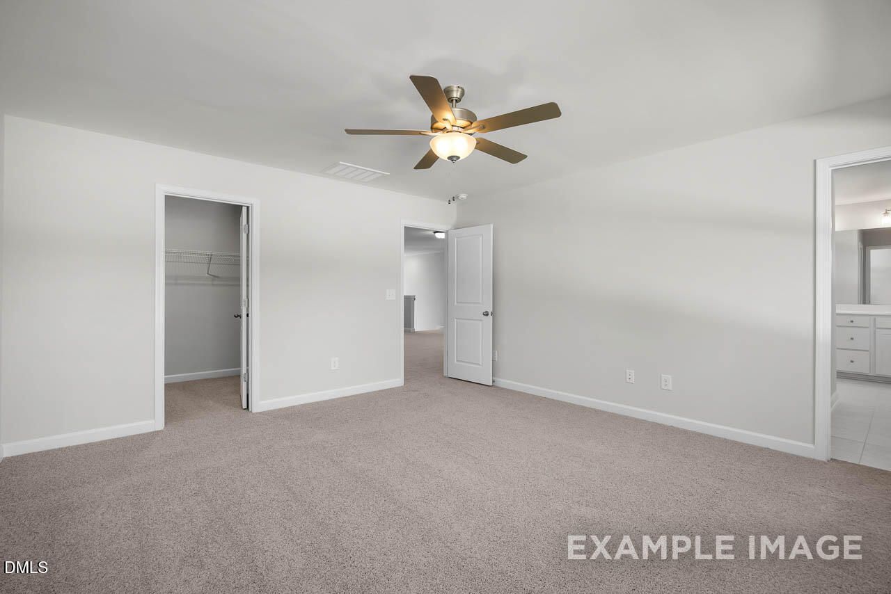 Spacious master bedroom with ceiling fan, walk-in closet, and en-suite bathroom in Davidson Homes The Adalynn A, Lillington, NC