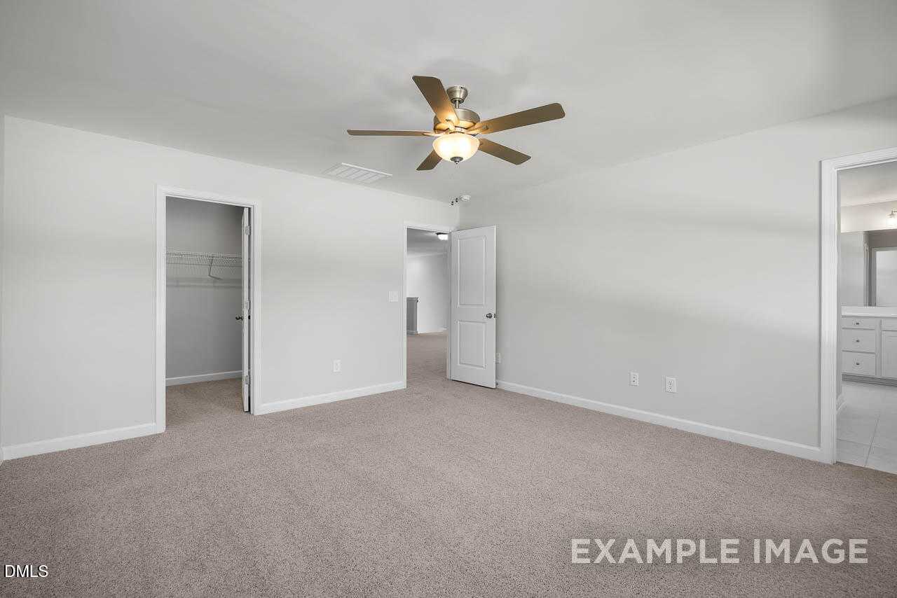 Spacious master bedroom with ceiling fan, walk-in closet, and en-suite bathroom in Davidson Homes The Adalynn A, Lillington, NC