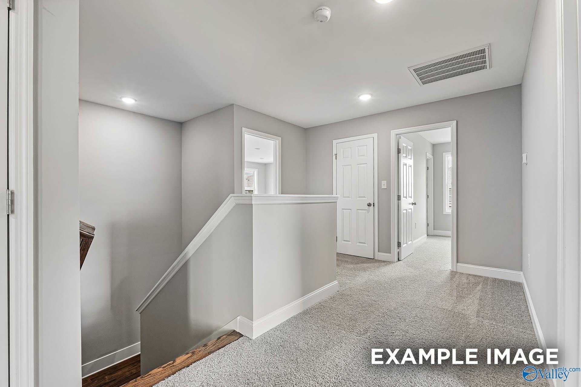 Modern upstairs hallway with bedroom doors, staircase railing, and gray walls in Davidson Homes The Chelsea A, Athens AL