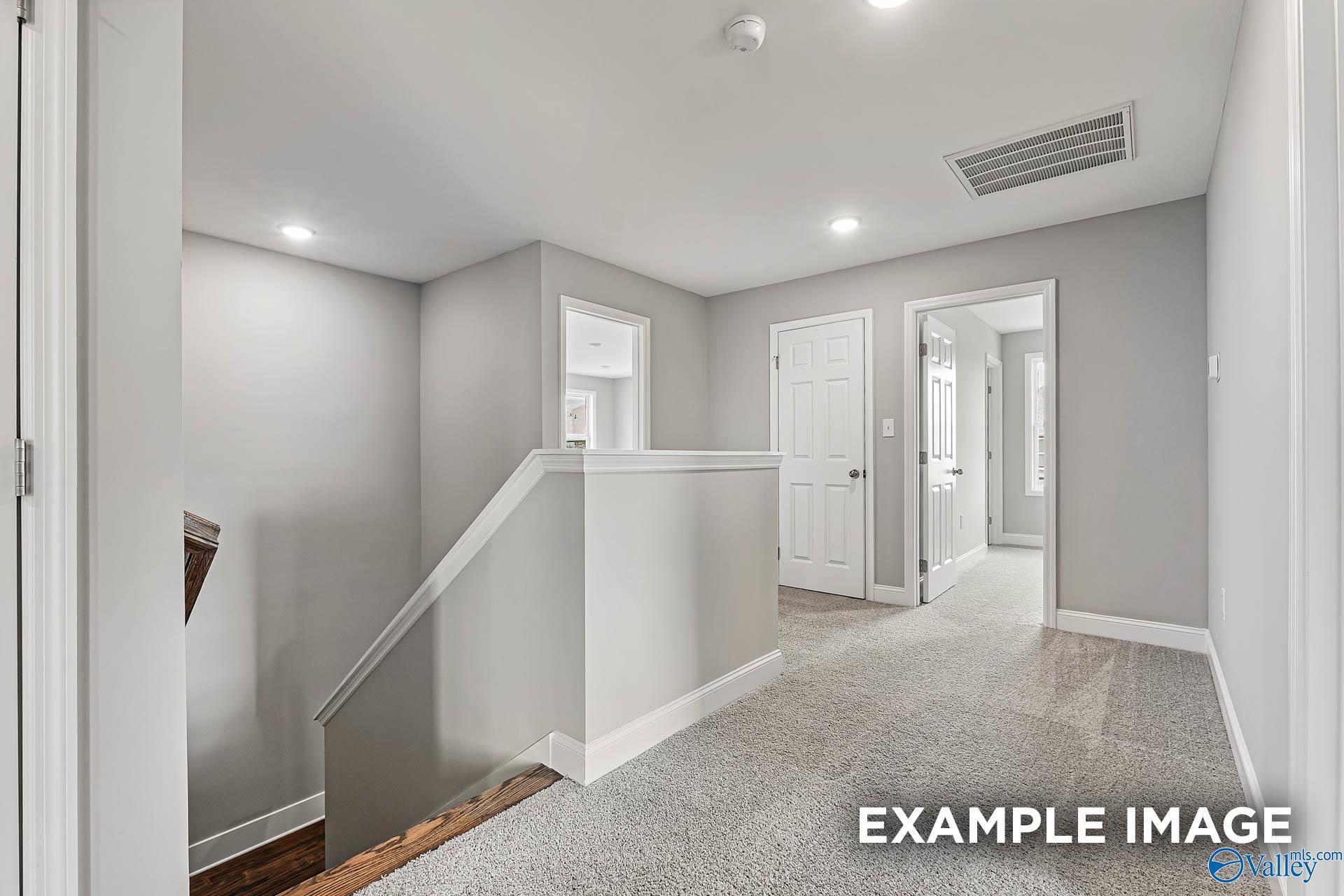 Bright upstairs hallway with gray walls, plush carpet, white bedroom doors, and modern staircase in Davidson Homes Chelsea B, Toney Alabama