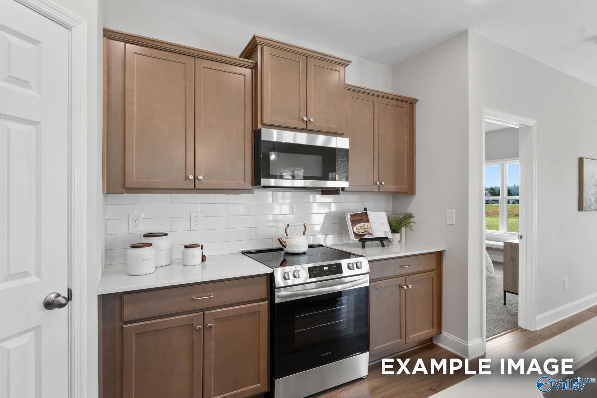Modern kitchen with oak cabinets, stainless steel oven and microwave, white subway tile backsplash in Davidson Homes The Franklin C, Meridianville, Alabama