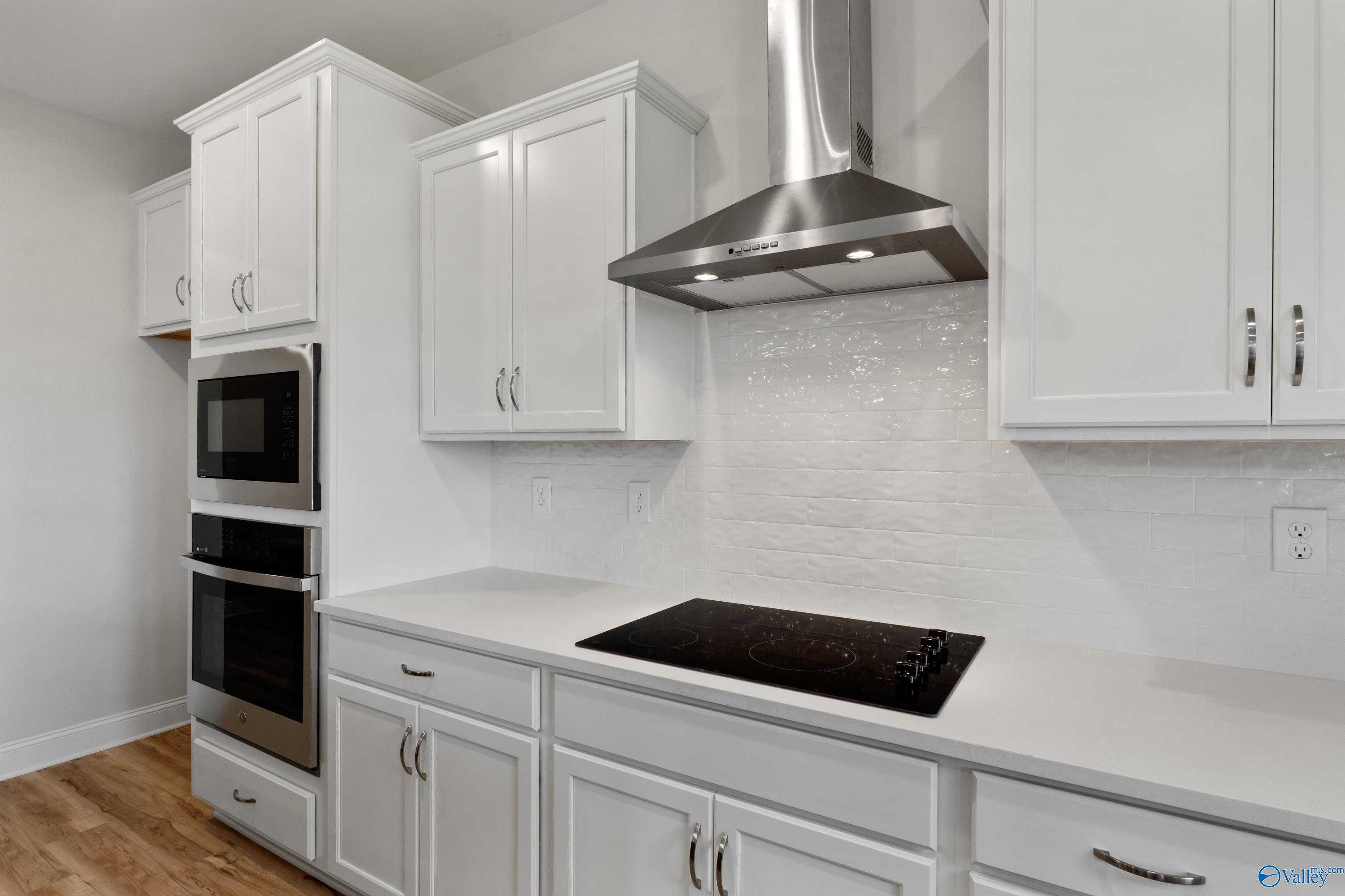 Modern white kitchen with shaker cabinets, stainless double oven, gas cooktop, and subway tile backsplash in Davidson Homes Chelsea C, Harvest AL