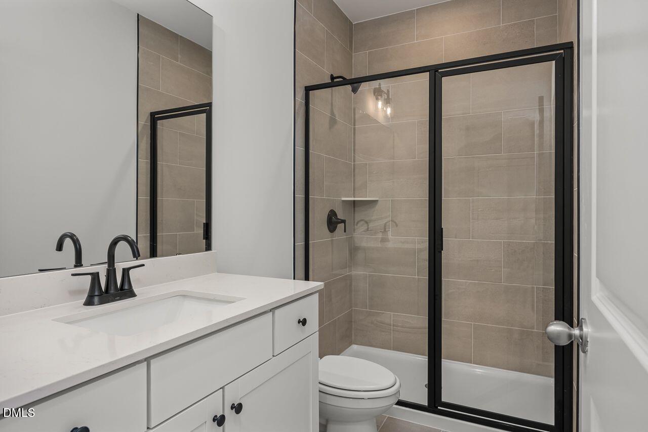 Modern bathroom with white vanity, black hardware, and tiled shower in The Birch II A floor plan at Montrose, Aberdeen, NC.