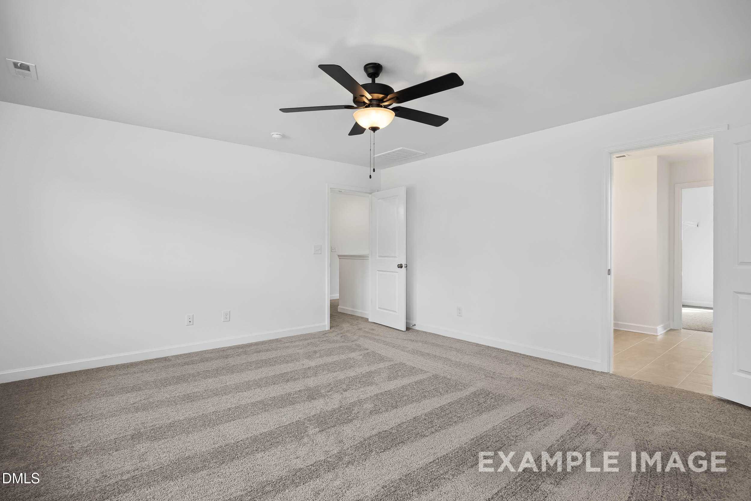 Spacious empty bedroom with ceiling fan, white walls, and beige carpet in Davidson Homes The Willow D, Zebulon, NC
