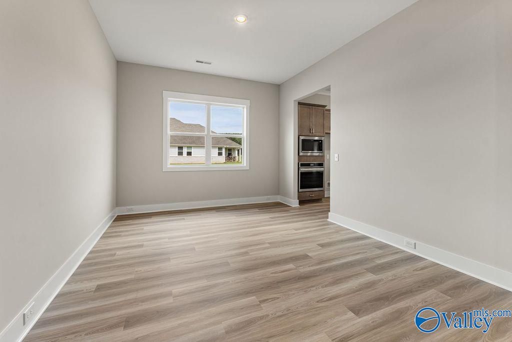 Bright bedroom with neutral walls, luxury vinyl plank floors, large window to neighborhood, open to kitchen with double ovens in Evermore Homes The Oxford, Owens Cross Roads