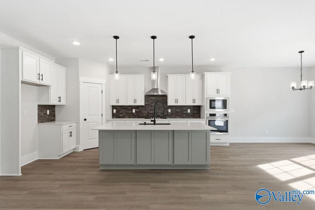 Modern open-concept kitchen featuring white shaker cabinets, gray island, stainless steel appliances, subway tile backsplash in Davidson Homes The Rockford, Hartselle, Alabama