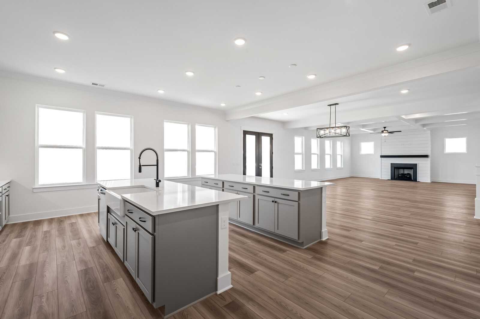 Modern open-concept kitchen with white cabinets, quartz island, black faucet, and fireplace living area in The Alston A, Murfreesboro, TN