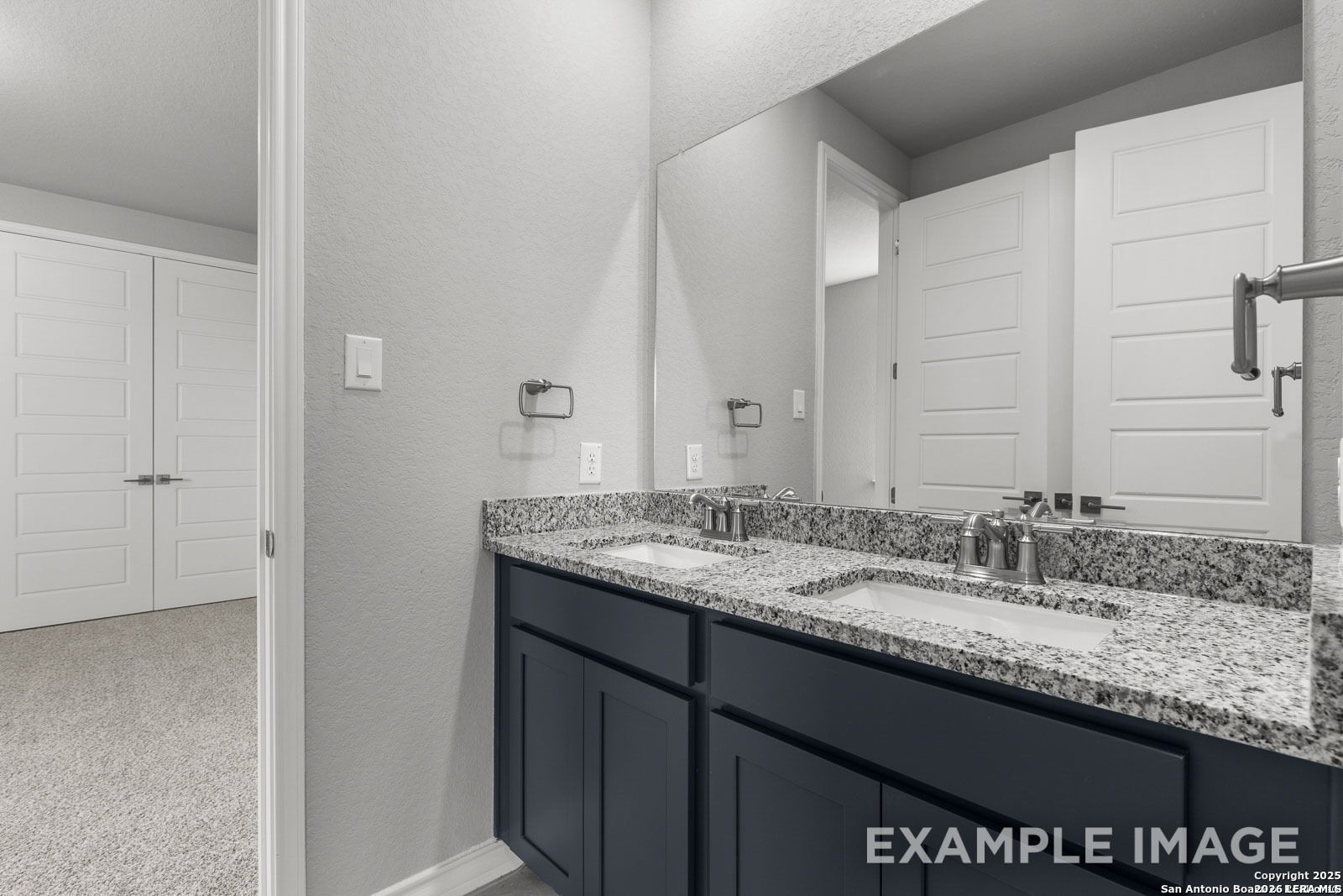 Modern bathroom with dual vanity, granite countertops, and dark cabinets in Davidson Homes The Oxford F, Potranco Oaks.