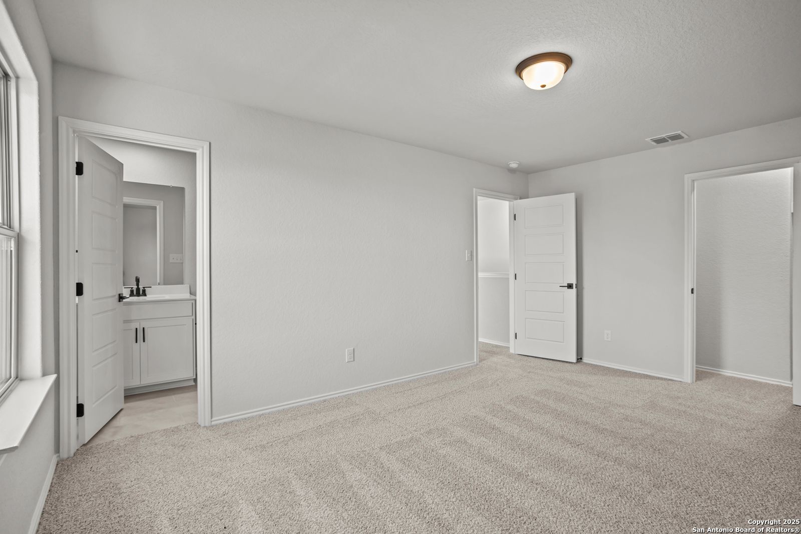 Bright secondary bedroom with beige carpet, attached bath vanity, and closet doors in Davidson Homes The Douglas C, Seguin, Texas