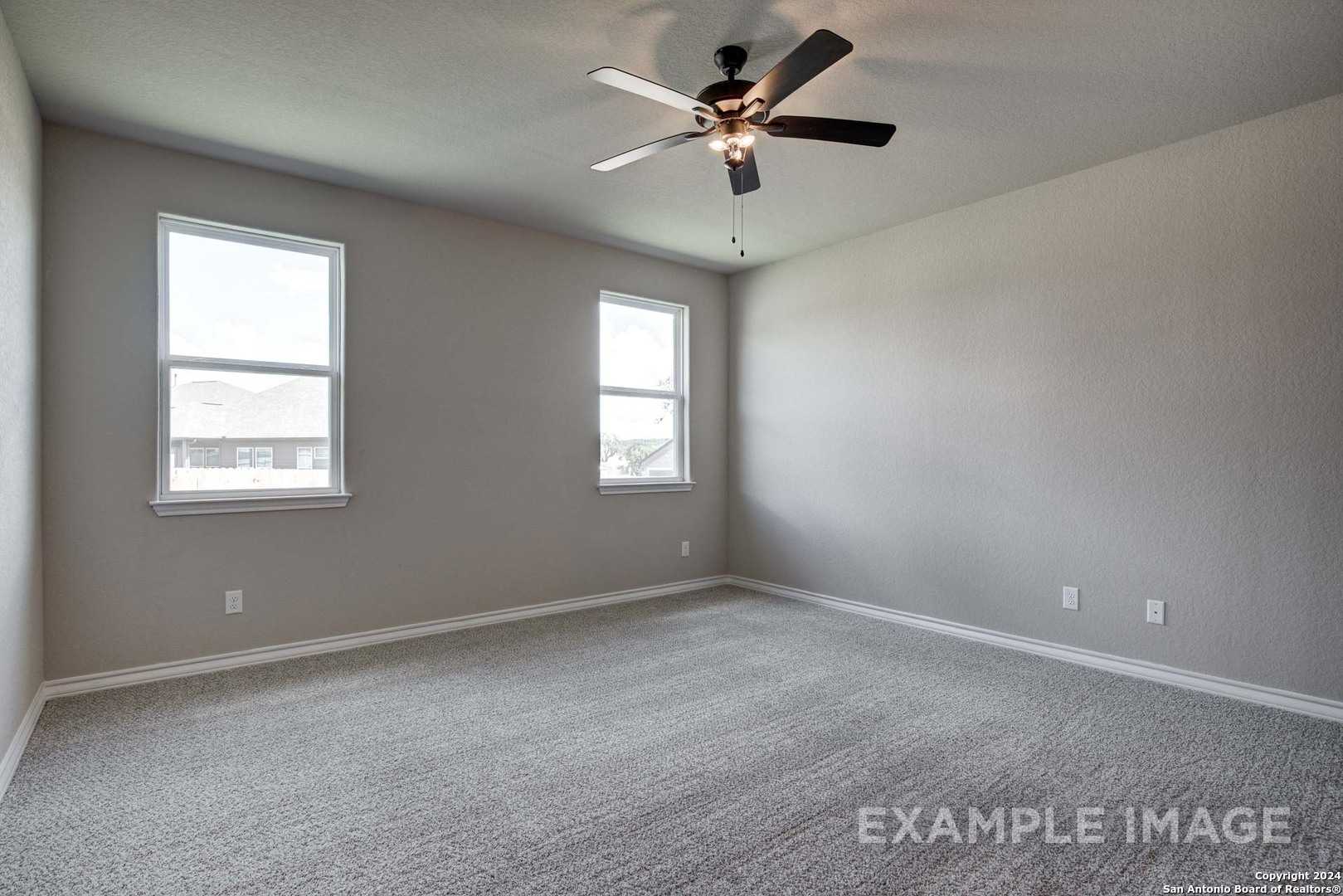 Bright secondary bedroom with dual windows, ceiling fan, and neutral gray walls in Davidson Homes The Rockford G, San Antonio, Texas