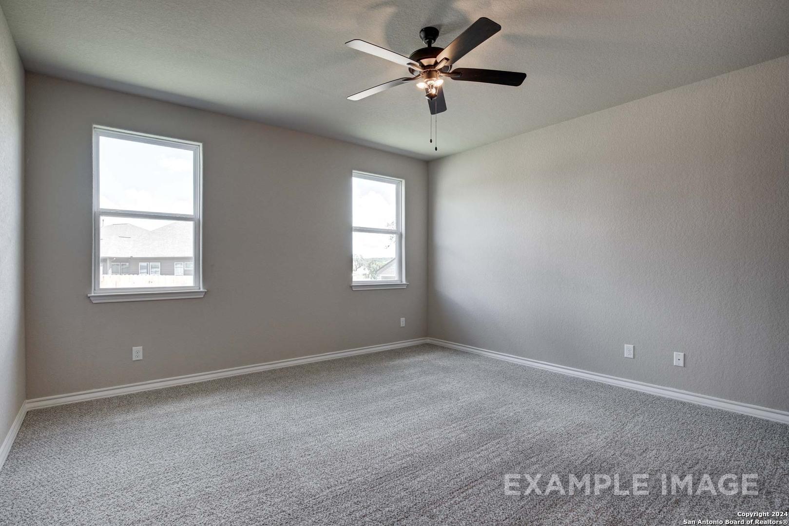 Bright secondary bedroom with dual windows, ceiling fan, and neutral gray walls in Davidson Homes The Rockford G, San Antonio, Texas