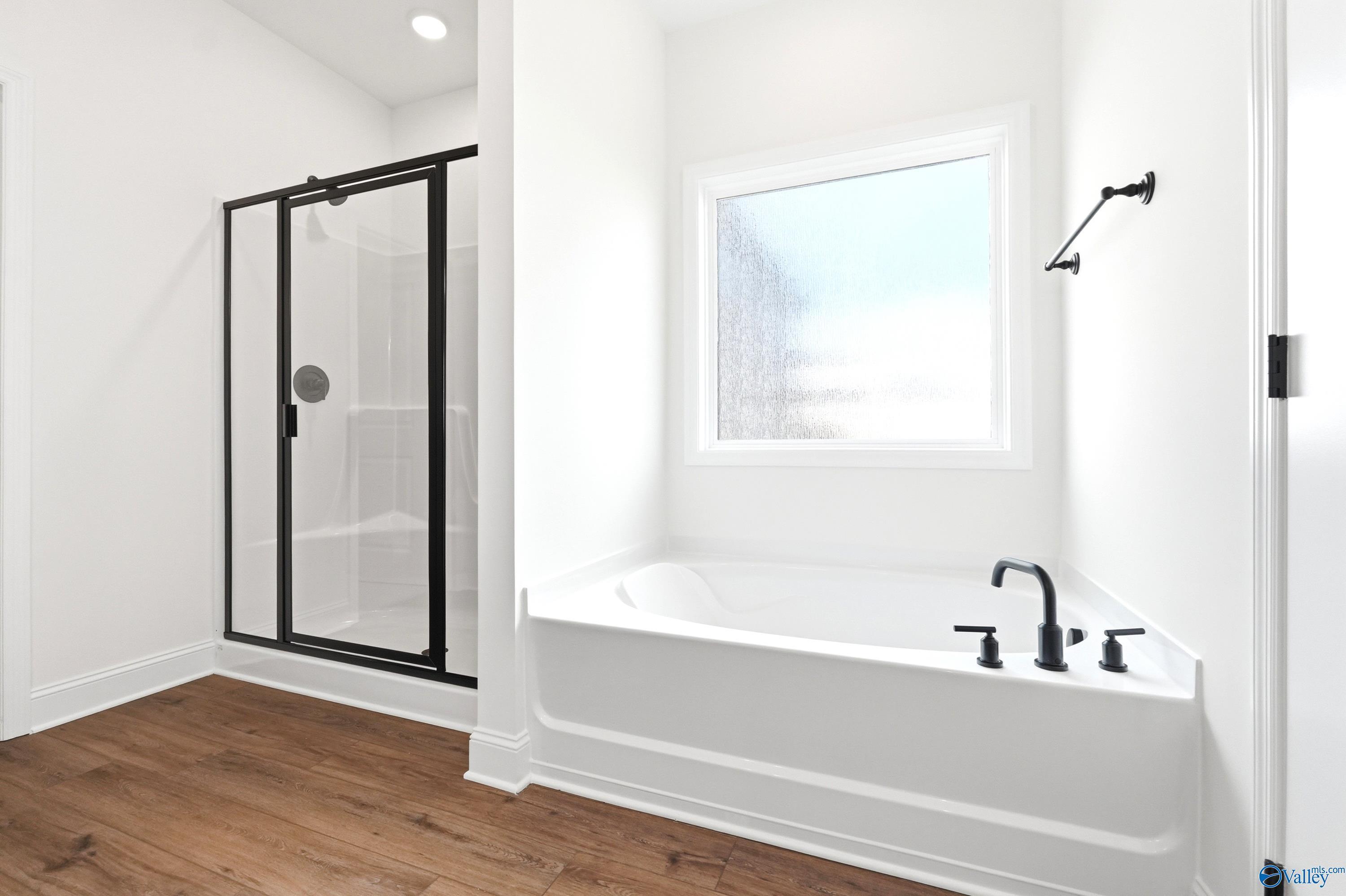 Modern primary bathroom with soaking tub and glass-enclosed shower in The Everett B floor plan by Davidson Homes.