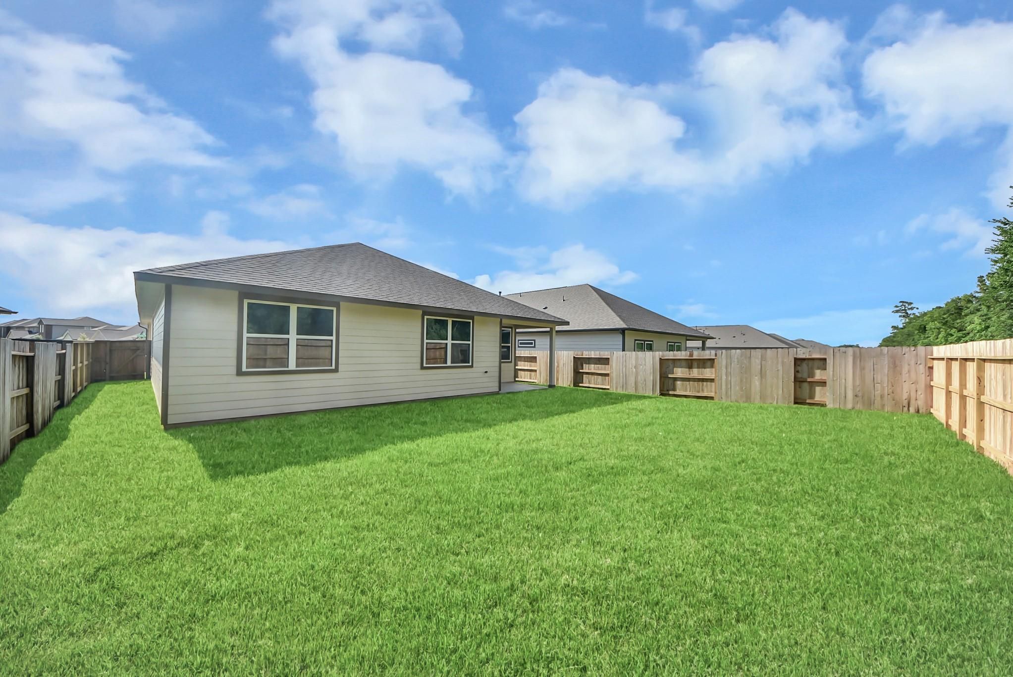 Spacious private backyard with wood fence at The Daphne F floor plan home in Sundance Cove, Crosby, Texas.
