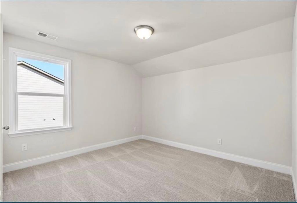 Bright, carpeted bedroom with neutral walls in The Ash C floor plan at Wehunt Meadows, Hoschton, Georgia.