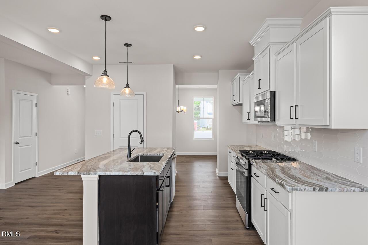Modern kitchen with marble-style countertops, white cabinetry, and pendant lighting in The Willow B, Zebulon, NC.