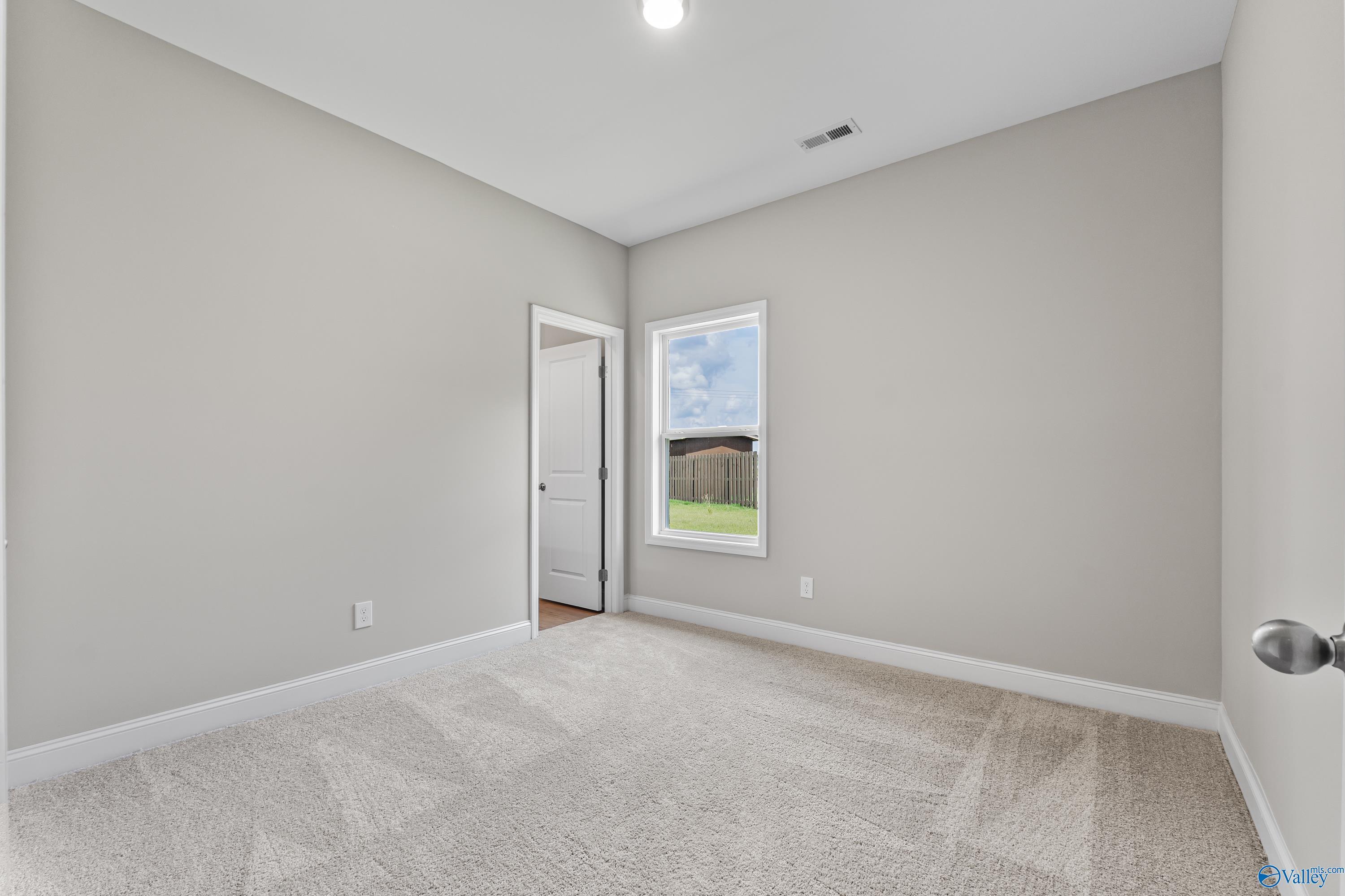 Bright secondary bedroom featuring gray walls, plush carpet, window with sky view in Davidson Homes The Daphne C, Harvest AL