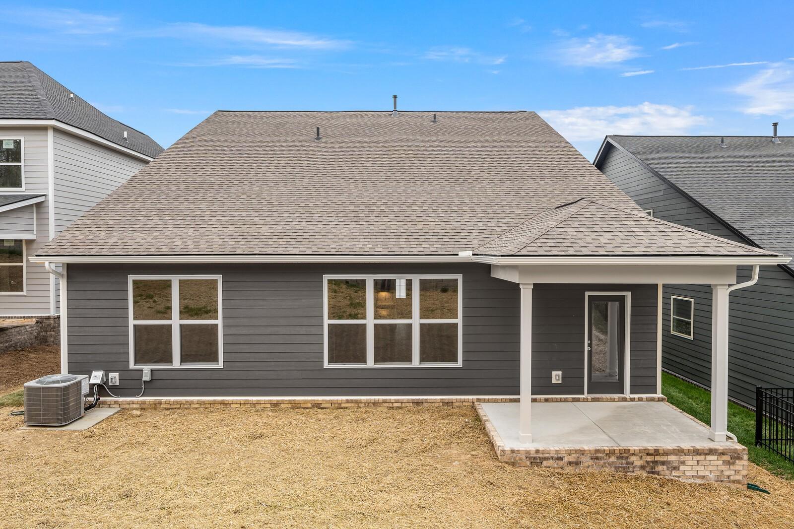 Rear view of The Ridgeport C two-story home with covered patio, large windows, and fenced backyard in Woods Crossing, Gallatin, Tennessee