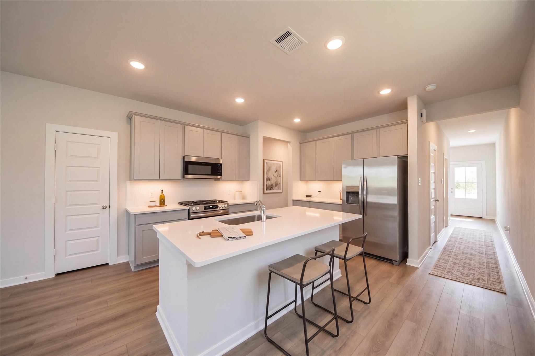 Bright kitchen with white island, stainless appliances, and gray shaker cabinets in Davidson Homes' The Frio F, Houston, TX