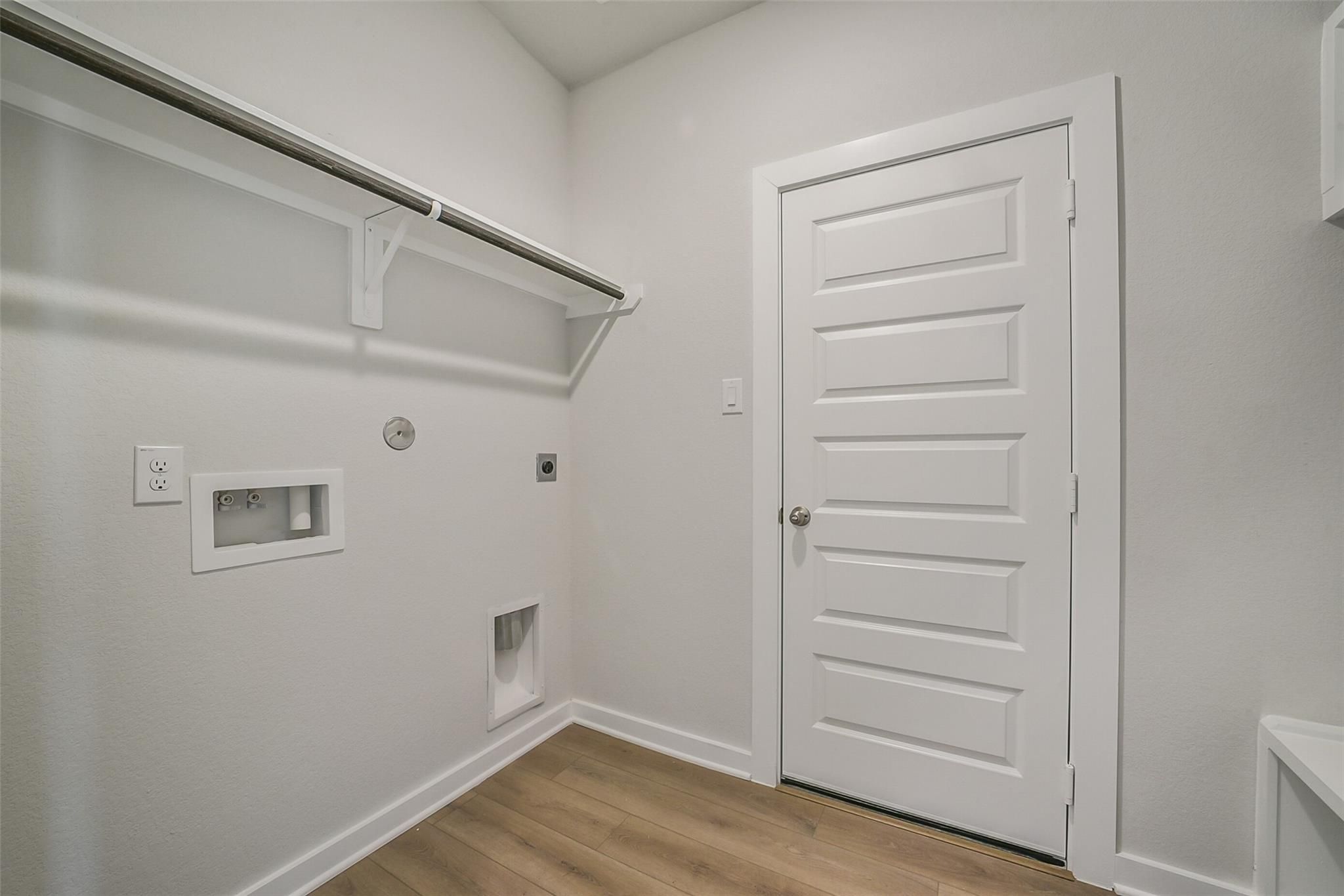 Spacious laundry room featuring washer/dryer hookups, built-in storage shelves, pet door, and white paneled door in Davidson Homes The Frio F, Conroe, Texas