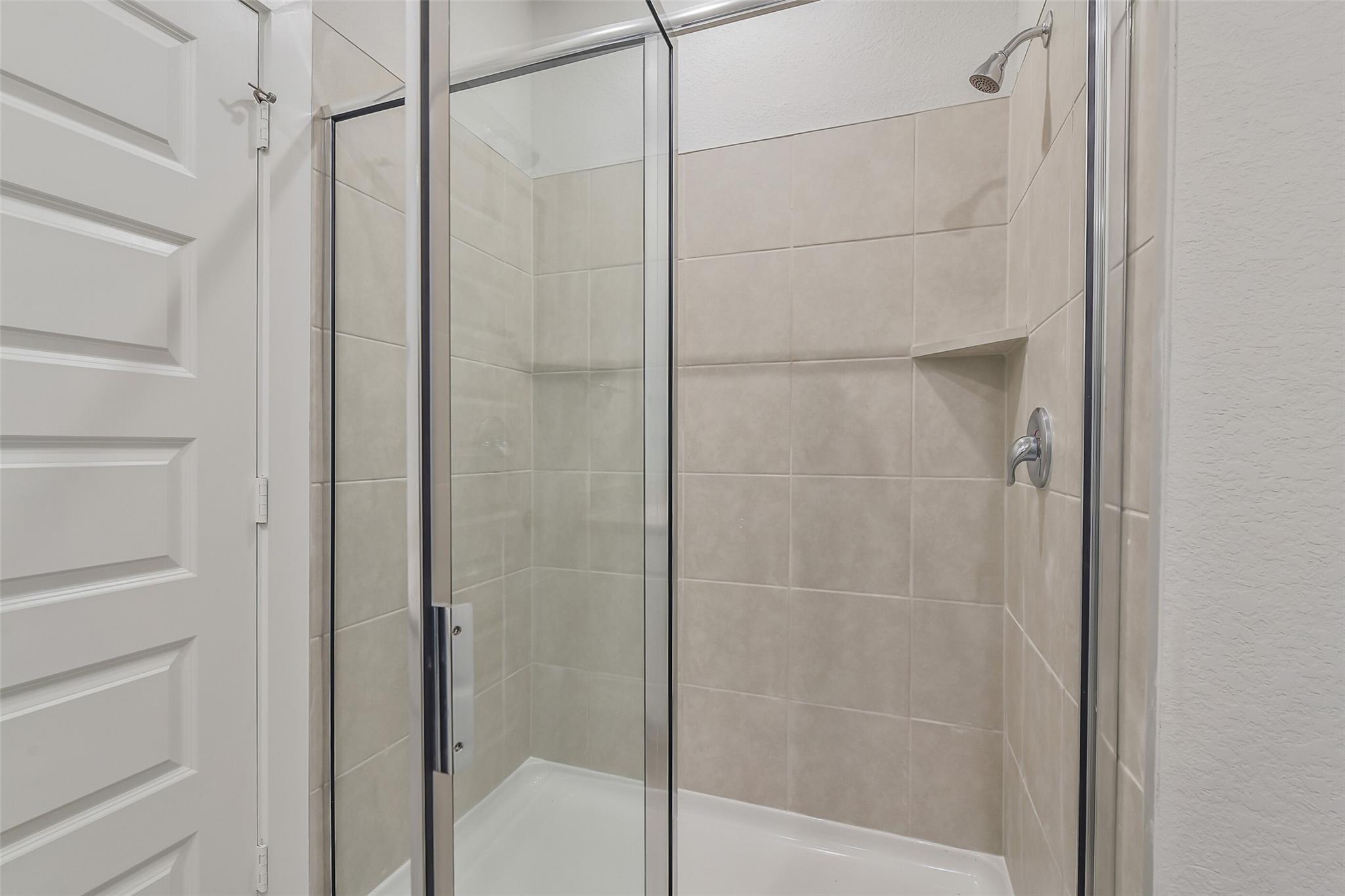 Frameless glass shower with subway tile surround and niche in Davidson Homes The Frio G bathroom, Cleveland, Texas