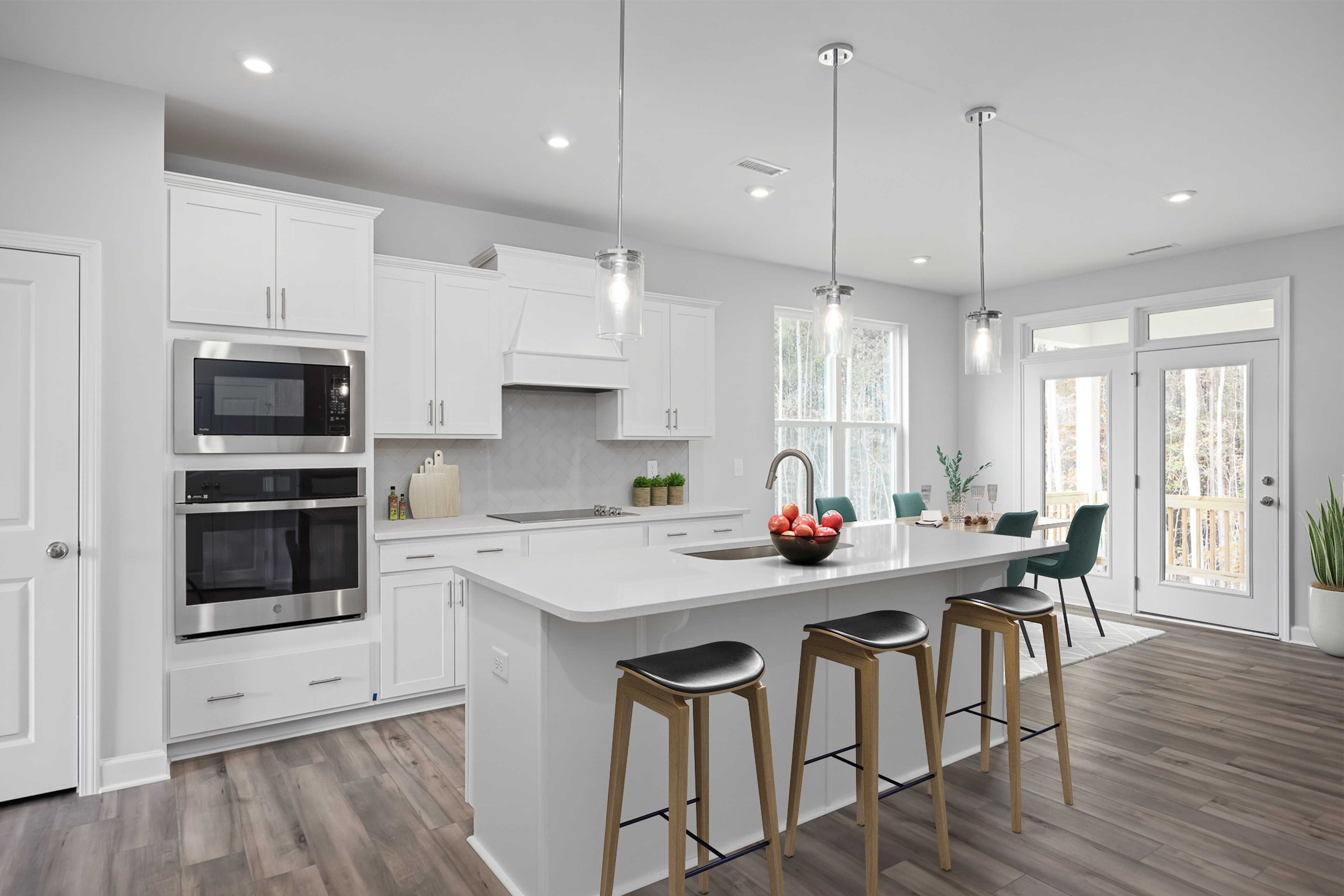 Modern kitchen at Stagecoach Corner in Mebane NC with white cabinets, stainless steel appliances, large island, bar stools, and hardwood floors