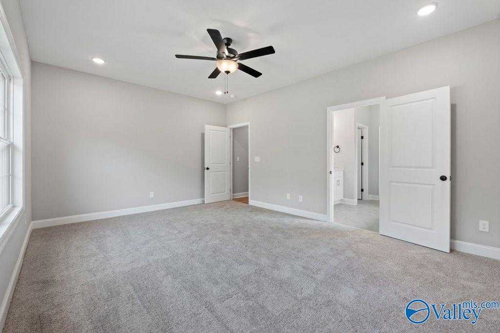 Spacious master bedroom with ceiling fan, gray carpet, and en-suite bath in Davidson Homes The Montgomery B, Hartselle, Alabama