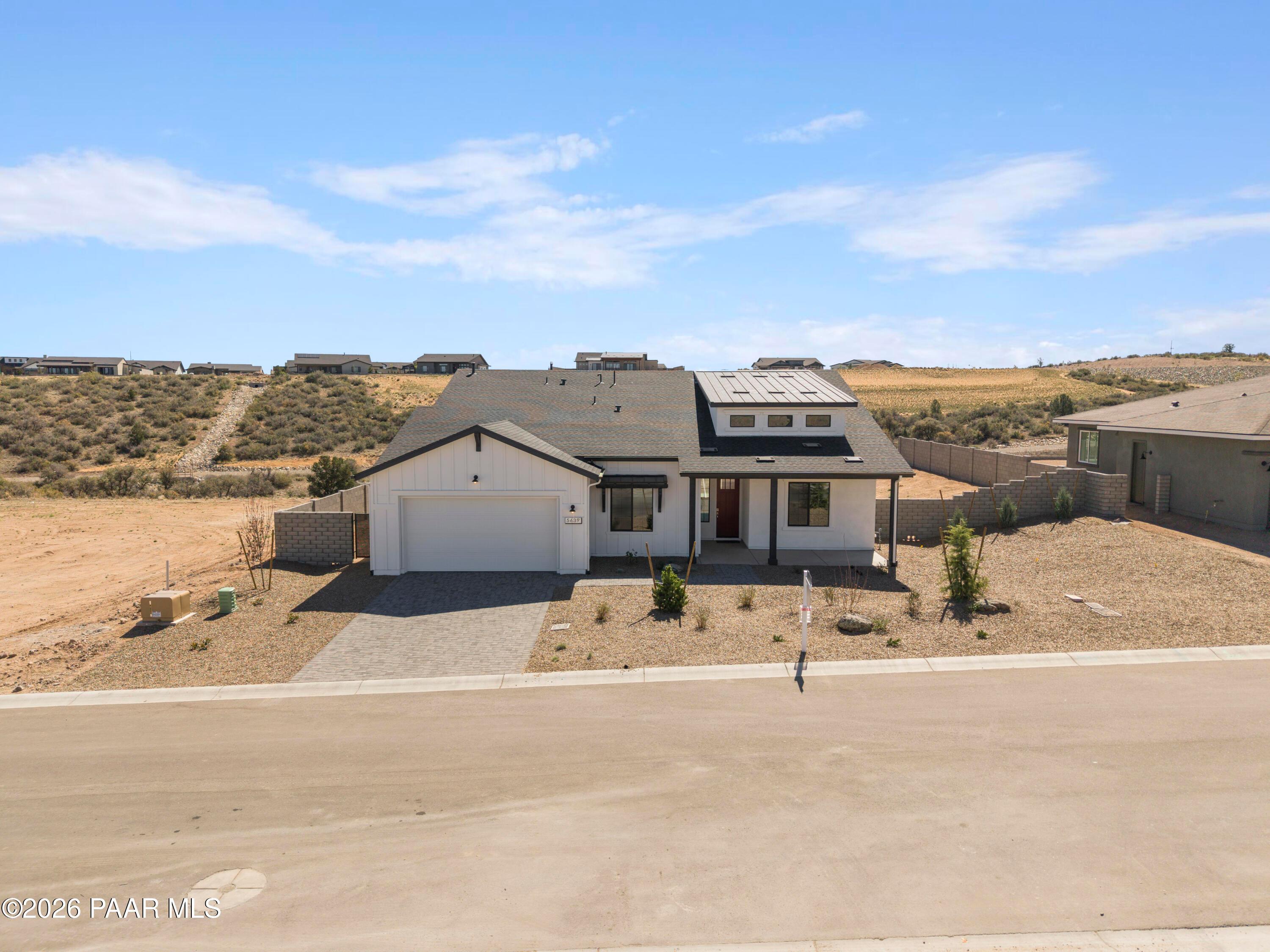 Modern white single-story home with 3-car garage, red door, and desert landscaping in Hidden Hills, Prescott, Arizona - Davidson Homes Soleil E