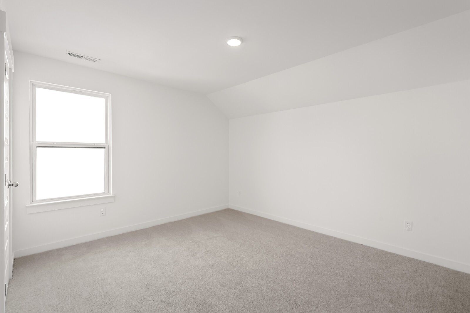 Bright empty bedroom with sloped ceiling, white walls, beige carpet, and large window in Davidson Homes The Ash C, Mt. Juliet