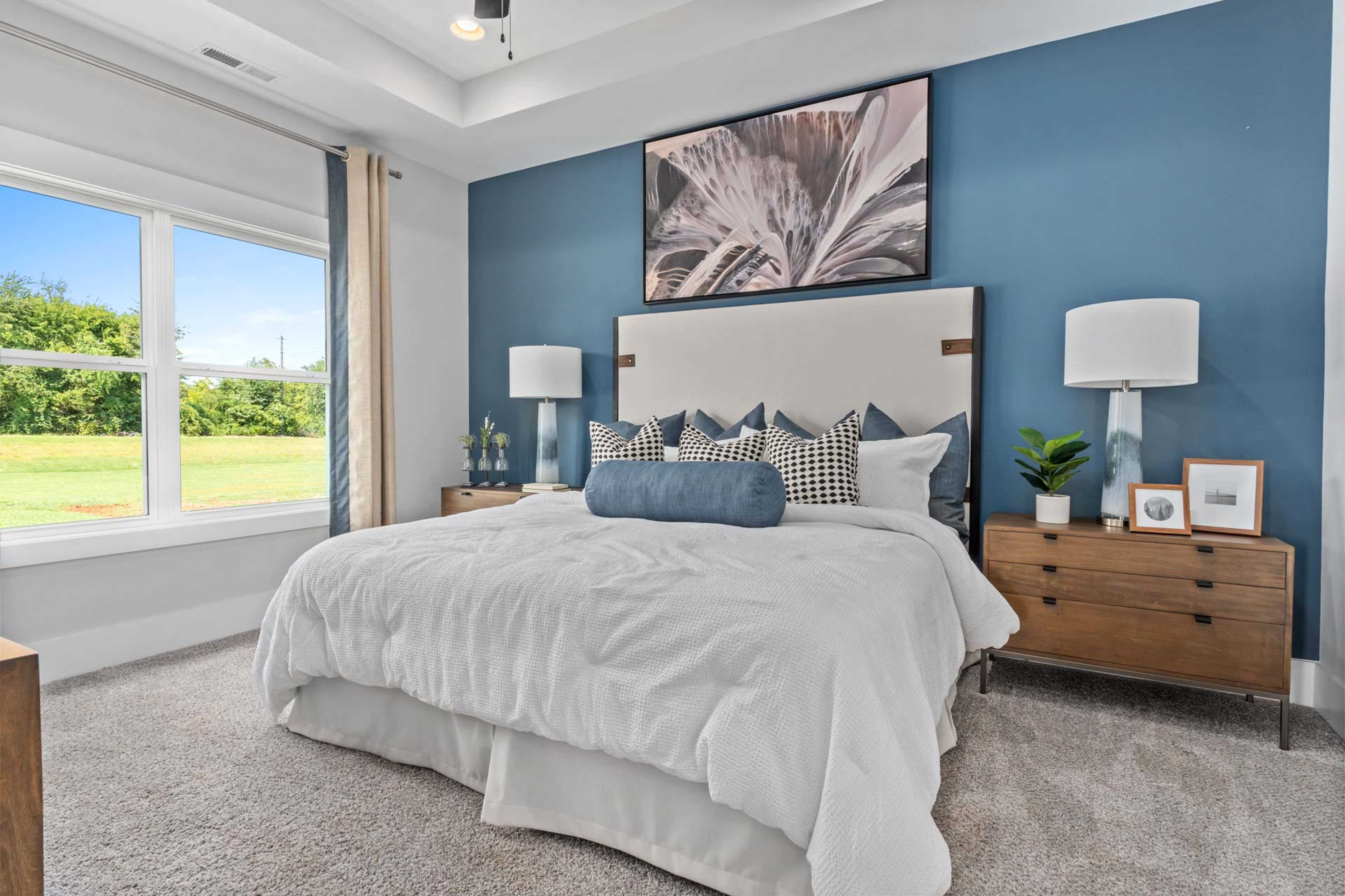 Serene master bedroom at Blue Spring in Huntsville AL with blue accent wall, king bed, and scenic window view