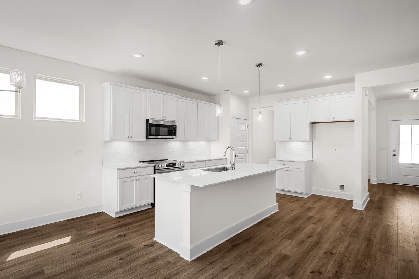 Modern white kitchen with quartz island in The Ash A floor plan at Woods Crossing, Gallatin, Tennessee.