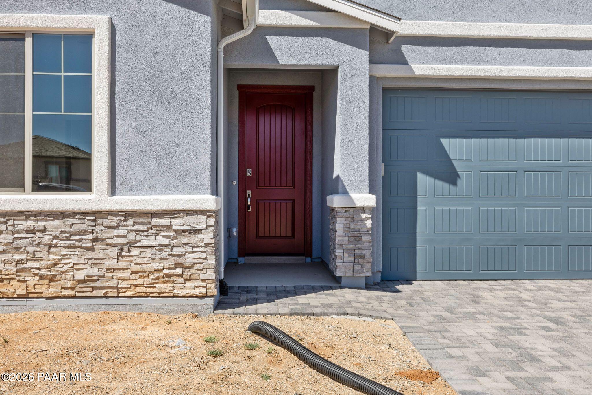 Exterior of Davidson Homes The Frontier A: gray stucco 1-story with red wood door, window, blue 3-car garage in Prescott Valley, AZ