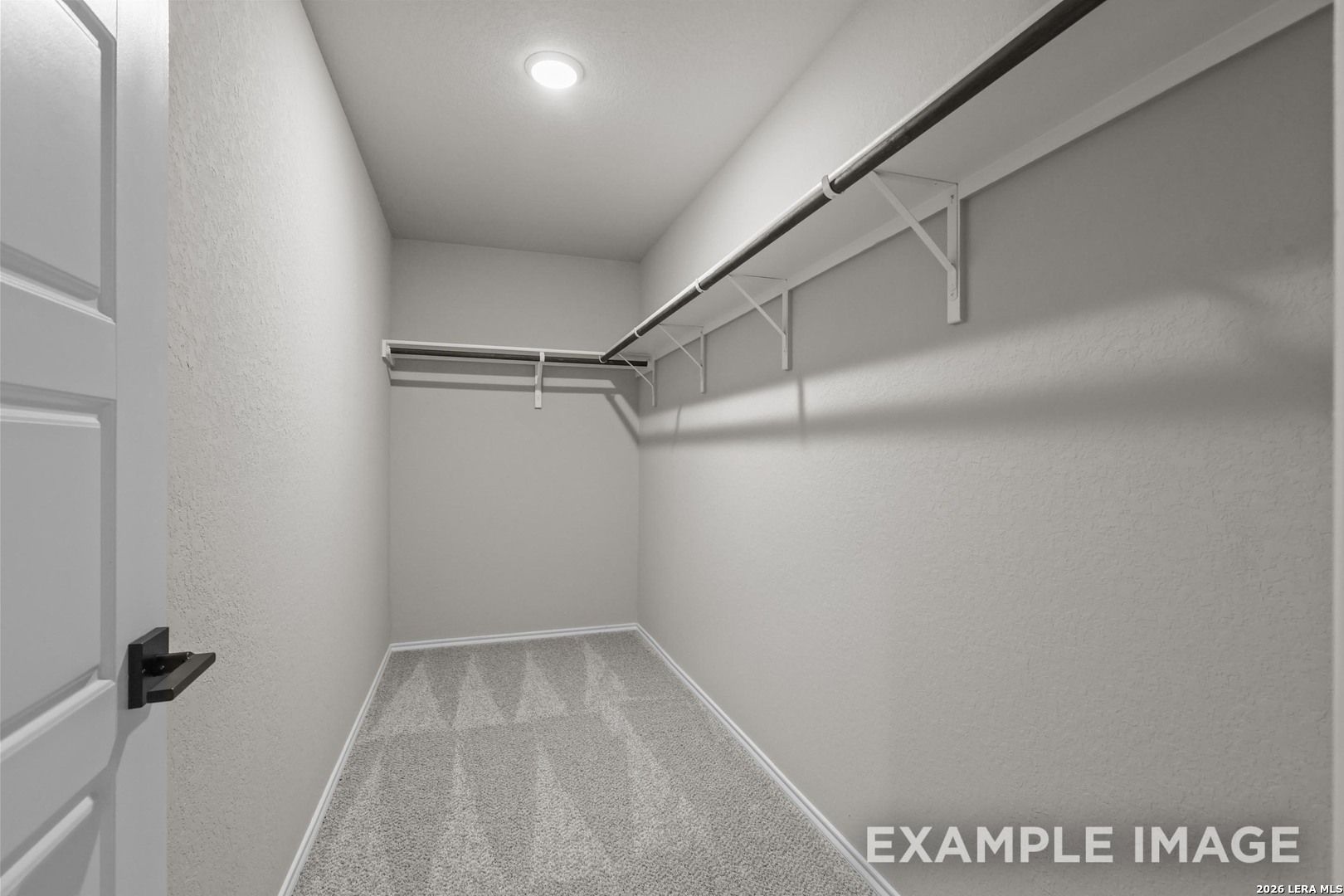 Spacious walk-in closet with dual hanging rods and carpet flooring in Davidson Homes The Murray H plan, Converse, Texas