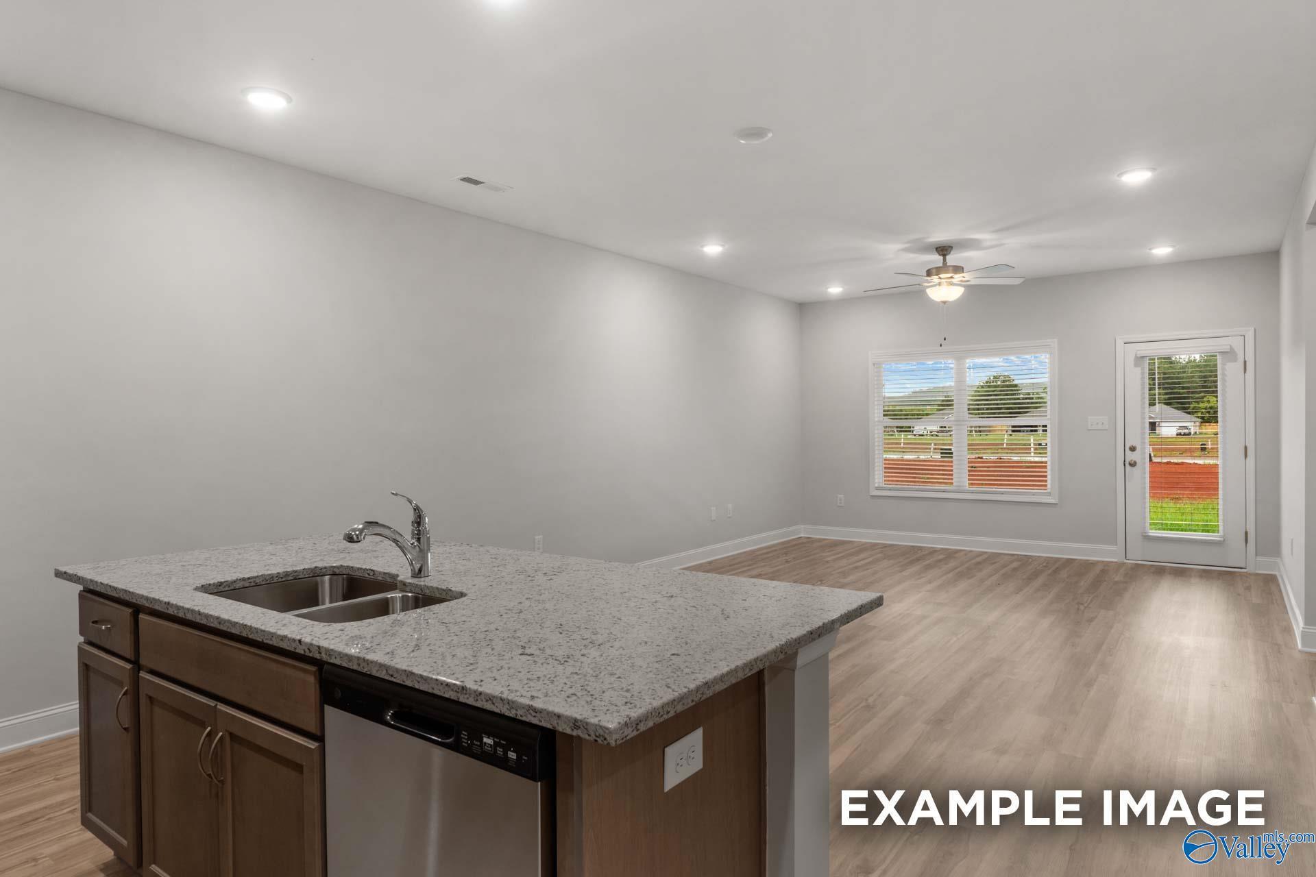 Modern open-concept kitchen with granite island sink, stainless dishwasher, and backyard view in Davidson Homes The Cumberland B, Decatur, AL