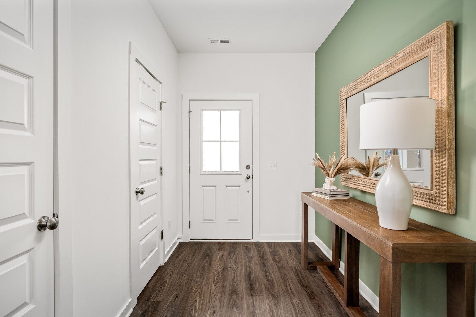Elegant entry foyer with green accent wall, ornate mirror, wooden console table, lamp, and hardwood floors in Davidson Homes The Gordon C, White House, TN