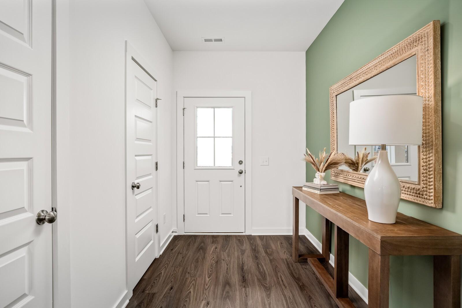 Elegant entry foyer with green accent wall, ornate mirror, wooden console table, lamp, and hardwood floors in Davidson Homes The Gordon C, White House, TN